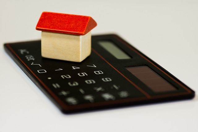 small toy house with a red roof sits on a black calculator